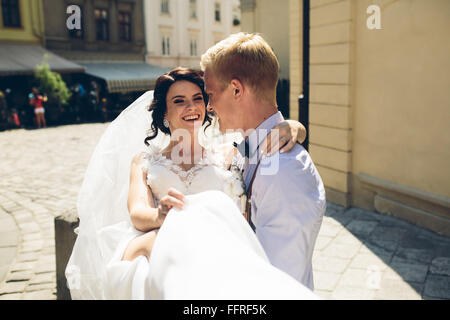 Lo sposo porta sposa nelle sue braccia Foto Stock