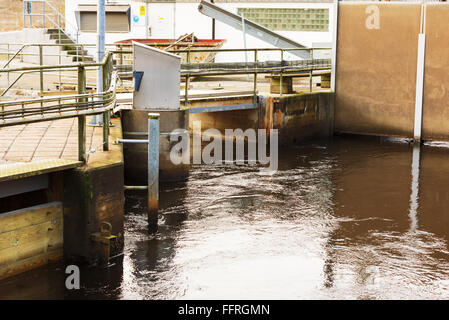 Djupafors, Svezia - Febbraio 07, 2016: un piccolo ponte che attraversa oltre la piccola diga idroelettrica. Lo streaming di acqua è costretto a re Foto Stock