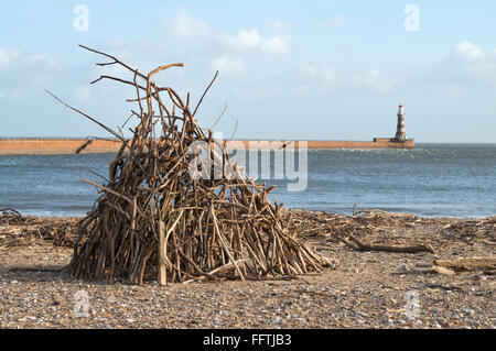 Driftwood si trova sulla spiaggia di Roker con il molo nord sullo sfondo, Sunderland North East England, Regno Unito Foto Stock