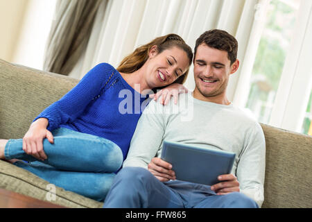 Coppia giovane seduto sul divano e con tavoletta digitale Foto Stock