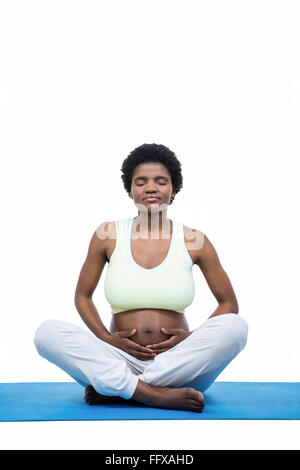 Donna incinta meditando sul tappetino Foto Stock