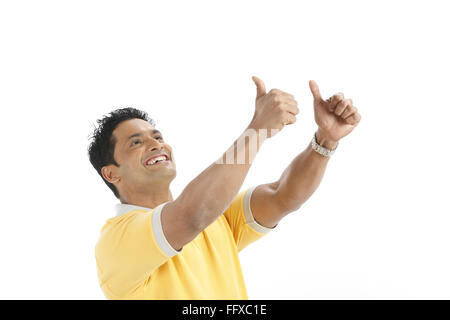 Fiducioso giovane uomo facendo azione vincente godendo di successo facendo pugno di entrambe le mani e il sollevamento verso l'alto signor#703R Foto Stock