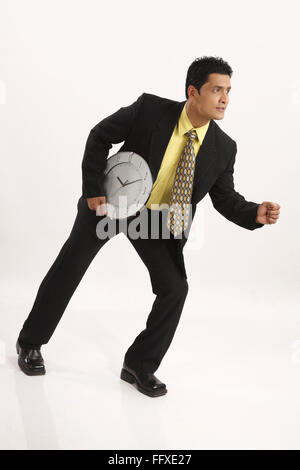 Imprenditore azienda orologio da parete in una sola mano accanto il suo lato destro della cintura e acceso il signor#703T Foto Stock