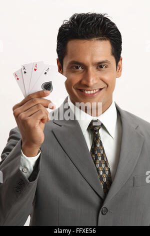Imprenditore azienda quattro assi di carte da gioco nel suo pollice e il dito indice della mano destra il signor#703T Foto Stock