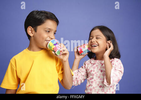 Dieci e otto anni che un ragazzo e una ragazza parlando sul bambino del telefono del fatto di due bicchieri e filo signor#703U, 703V Foto Stock