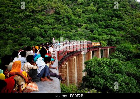 Pendolari seduti sul tetto del treno sul ponte ; Kamali Ghat ; Rajasthan ; India Foto Stock
