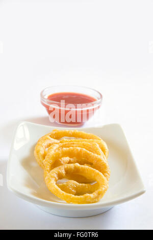 La cucina indiana , fast food antipasti Kandy Bhaji croccanti frittelle di cipolla anelli servita con il ketchup piatto fondo bianco Foto Stock