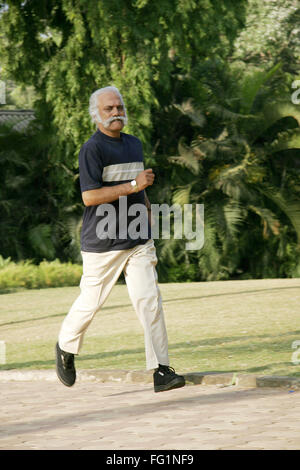 Anziano gentiluomo oltre sessanta anni in blu scuro di T-shirt e color beige pant jogging nel parco per mantenere se stesso montare signor#671 Foto Stock