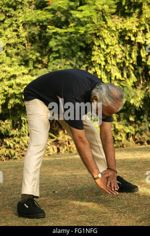 Anziano gentiluomo in blu scuro T shirt oltre sessanta anni di età facendo ginnastica mattutina nel parco per mantenere se stesso montare signor#671 Foto Stock