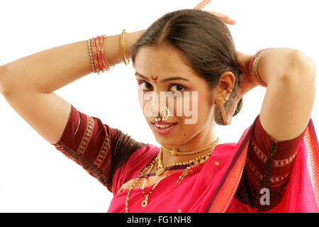 South Asian Indian Maharashtrian ragazza indossando il tradizionale navwari sari appropriate jewelry cercando regolare i capelli lunghi Foto Stock