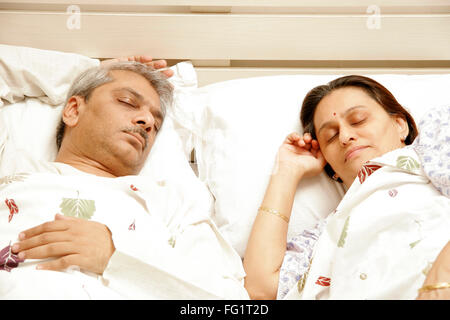 South Asian Indian Coppia di mezza età avente suono addormentato sul letto signor#686F,646 Foto Stock