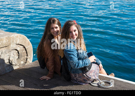 Due belle ragazze seduti vicino al mare sulle scale di un molo a Barcellona, in Catalogna, Spagna Foto Stock