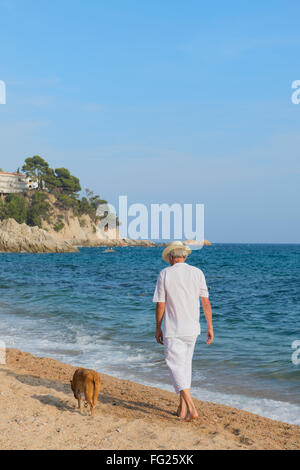 Senior Uomo con cane in abito bianco a piedi la spiaggia Foto Stock