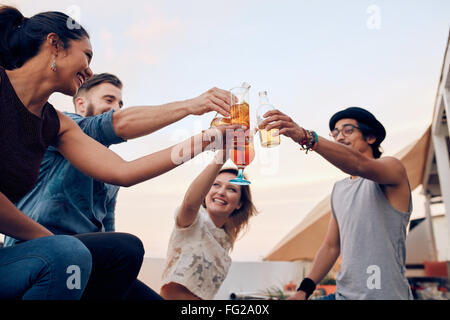 Ritratto di giovani cocktail di tostatura durante una festa. Quattro giovani amici godendo di un partito. Giovane uomo e donna appeso Foto Stock