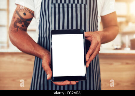 Tagliate il colpo di un uomo in un coffee shop con in mano una tavoletta digitale con display vuoto Foto Stock