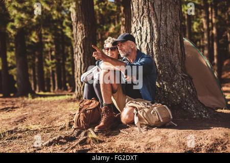 Ritratto di Coppia matura in un momento di relax a loro campeggio con uomo che mostra qualcosa da donna. Coppia senior escursionismo e campeggio in fo Foto Stock