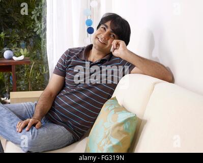 Giovane uomo che parla su cellulare seduti sul divano signor#702V Foto Stock