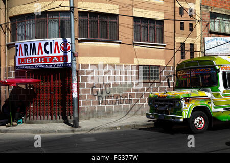 Microbus verde che passa davanti ai graffiti del dittatore Evo/dittatore Evo sulla parete dell'edificio Farmacia Libertad/Liberty o Freedom Pharmacy, la Paz, Bolivia Foto Stock