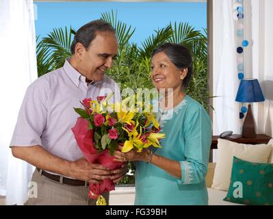 Vecchia coppia holding bouquet guardando ogni altro signor#702T, 702S Foto Stock