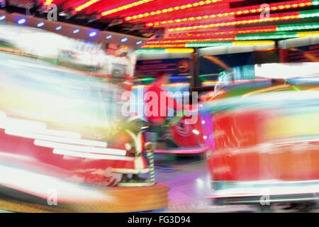 Fiera luna park ride movimento veloce fiera notte luci di colori del parco dei divertimenti di luci in movimento, sentieri di luce, lenta velocità otturatore Foto Stock