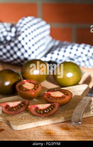 Dimezzate i pomodori scuro sul tavolo da cucina Foto Stock