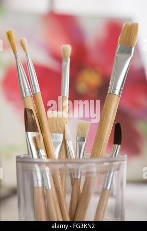 Pennelli in contenitore con pittura in background Foto Stock