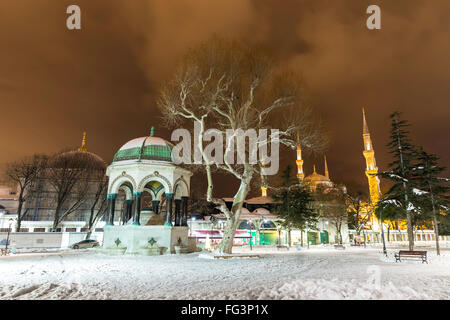 Nevoso inverno vista notturna della moschea di Sultanahmet e la Fontana di tedesco Foto Stock