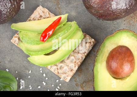 Fette di avocado su un pane croccante. Foto Stock