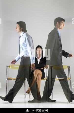 South Asian Indian executive donna seduta e gli uomini camminare MR Foto Stock