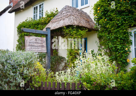Portico con tetto in paglia tetto sulla parte anteriore di una casa per le vacanze in Lulworth, Dorset con un grazioso giardino anteriore Foto Stock