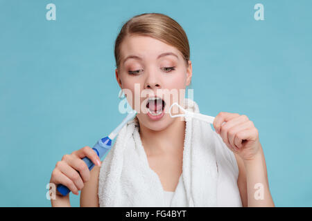 Ragazza giovane e carina utilizzando scopa elettrica e la linguetta detergente con bocca aperta. Donna felice lei per la pulizia della cavità orale cura. Foto Stock