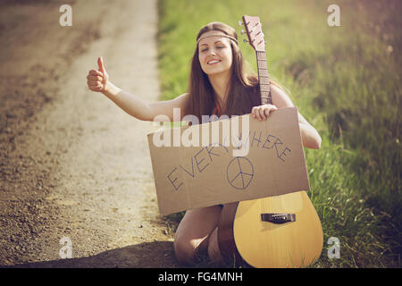 Hippie donna su una strada di campagna sollevatore-escursionismo . Viaggi e libertà Foto Stock