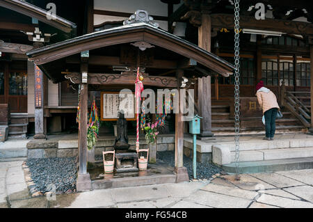 Tokyo, Giappone - 13 Gennaio 2016: Un donne giapponesi in preghiera nell'Jōen-ji di Shinjuku, Tokyo. Foto Stock