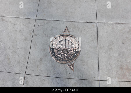 Medaglione di bronzo e frecce incorporato nella marcatura sul marciapiede di Barbary Coast Trail del sito storico di San Francisco, CA Foto Stock