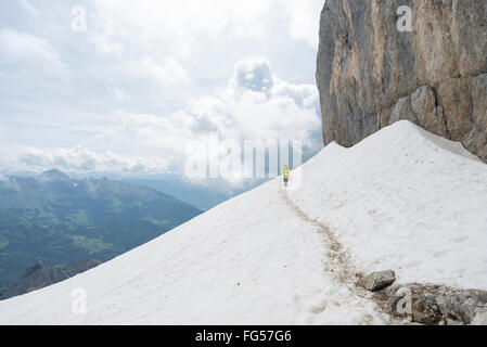 Escursionista maschio croce camminare un campo di neve sotto la rupe del vertice del monte Tournette mountain al Lago di Annecy in Savoia,Francia Foto Stock