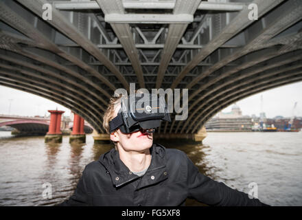 I giovani adulti utilizzando una realtà virtuale al di sotto del ponte. Foto Stock