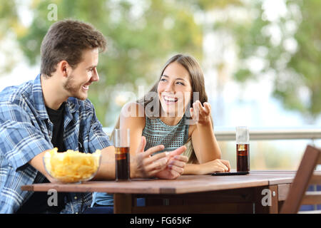 Ragazza parlando con un amico in una terrazza con snack e bevande Foto Stock