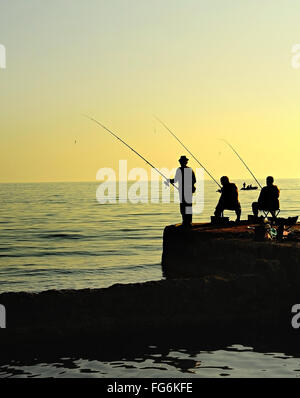 Gruppo di pescatori su un molo al tramonto. Penisola di Crimea Foto Stock