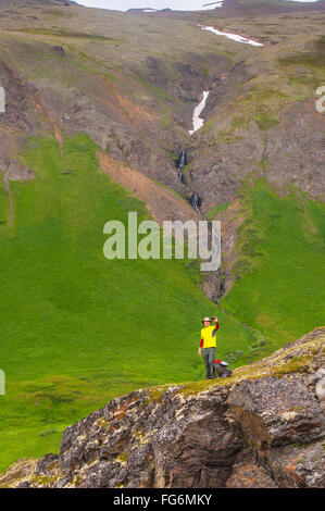 Un uomo escursionismo in Valle pensile prende un selfie con una cascata in background in Sud forcella in prossimità Eagle River, centromeridionale Alaska, estate Foto Stock