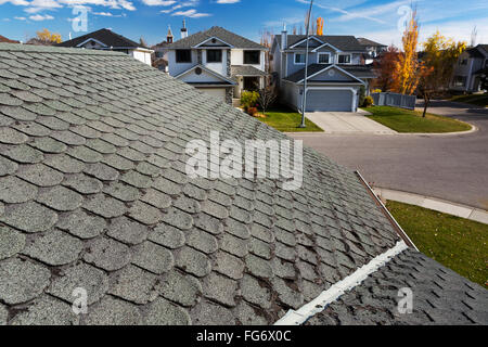 Dettaglio del bene arrotondata usurata di tegole con case di quartiere, i colori autunnali, cielo blu e nuvole in background; Calgary, Alberta, Canada Foto Stock