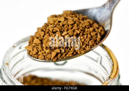 In prossimità di una cucchiaiata di granuli di caffè su jar contro uno sfondo bianco Foto Stock