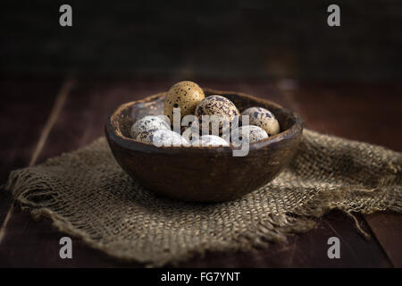 Organico fresco uova di quaglia in vaso di ceramica sulla biancheria rag. Luce naturale, il fuoco selettivo Foto Stock