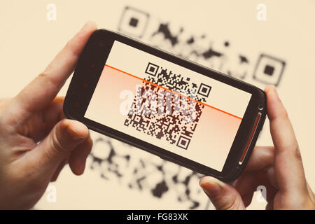 Due mani in possesso di un telefono cellulare mediante la scansione di un codice QR Foto Stock
