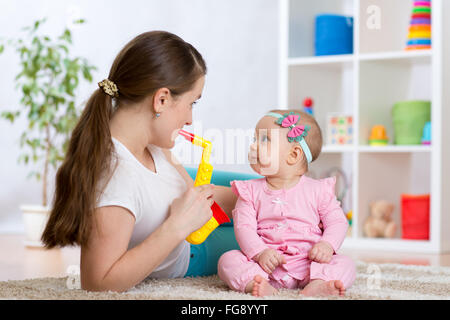 La famiglia felice la mamma e figlia bambino giocare giocattoli musicali Foto Stock