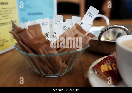 Bustine di zucchero bianco e marrone con la tazza di caffè in un bar Foto Stock