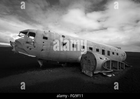 Bianco e nero orizzontale vista laterale di un relitto aereo sulle sabbie nere e sullo sfondo di un cielo blu nel sud dell'Islanda Foto Stock