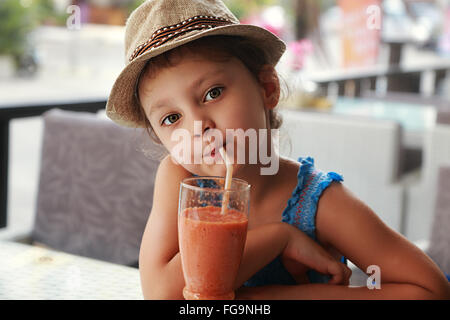 Divertimento carino kid ragazza bere il frullato sano succo in street restaurant. Closeup ritratto Foto Stock