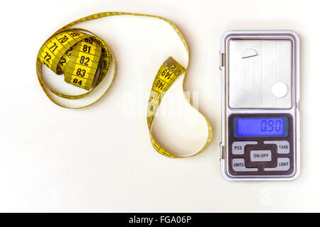 Nastro di misurazione e una medicina scala su uno sfondo bianco Foto Stock