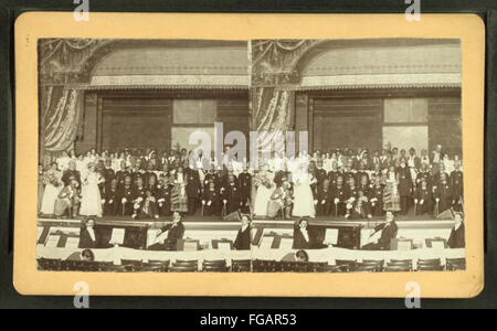 (Artisti interpreti o esecutori in costume in posa sul palco con musicisti in fossa, visto attraverso orchestra posti a sedere, da Robert N. Dennis raccolta di vista stereoscopica Foto Stock