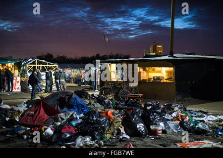 La spazzatura si accumula in un'area aperta di fronte ad un ristorante cafe e un negozio nella giungla campo profughi a Calais, Francia. Foto Stock